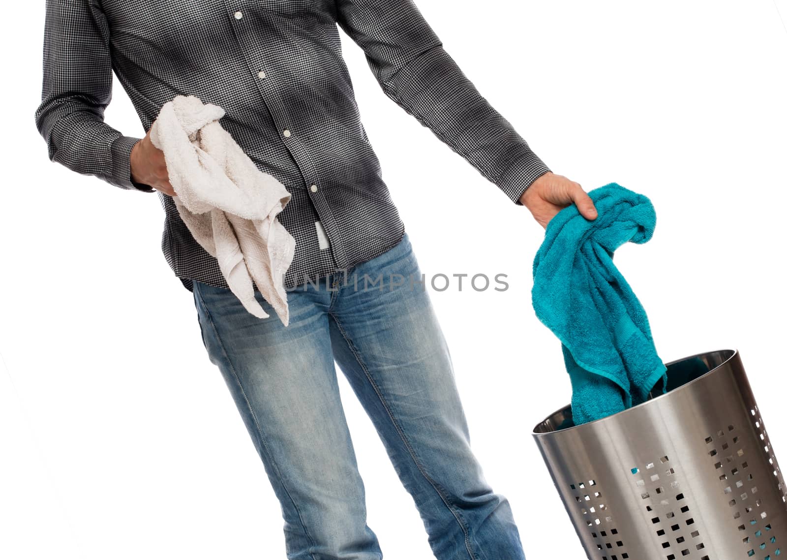 Young man putting a dirty towel in a laundry basket by michaklootwijk