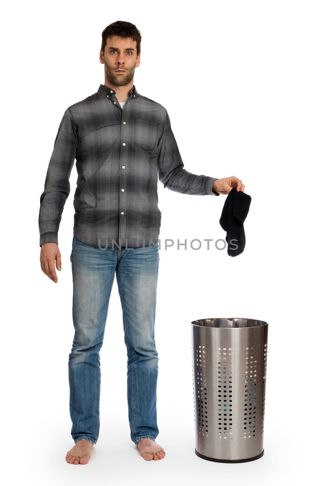 Young man putting dirty socks in a laundry basket, isolated on white