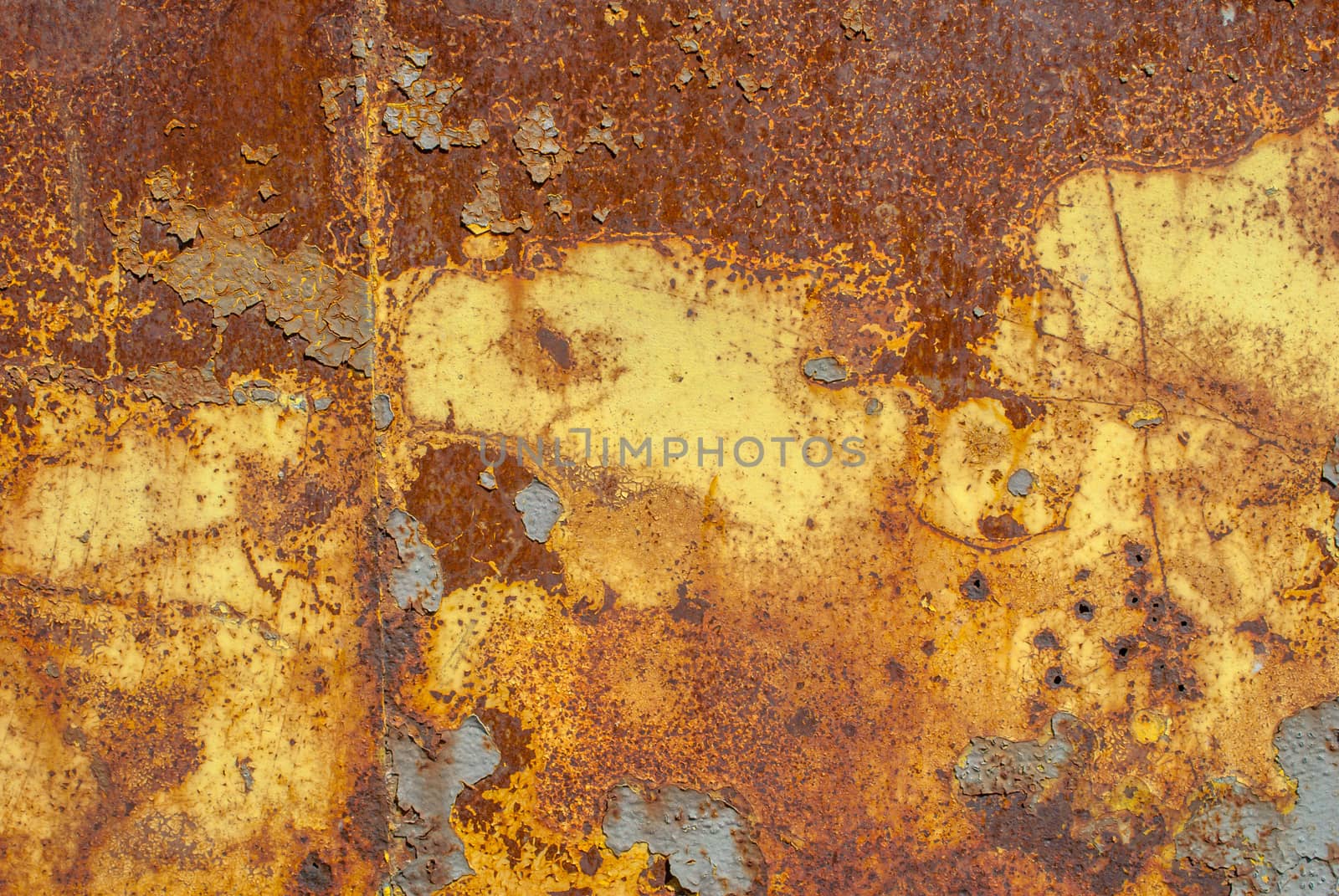rusty iron surface covered with old chipped yellow color paint, which has long been influenced by different climatic conditions