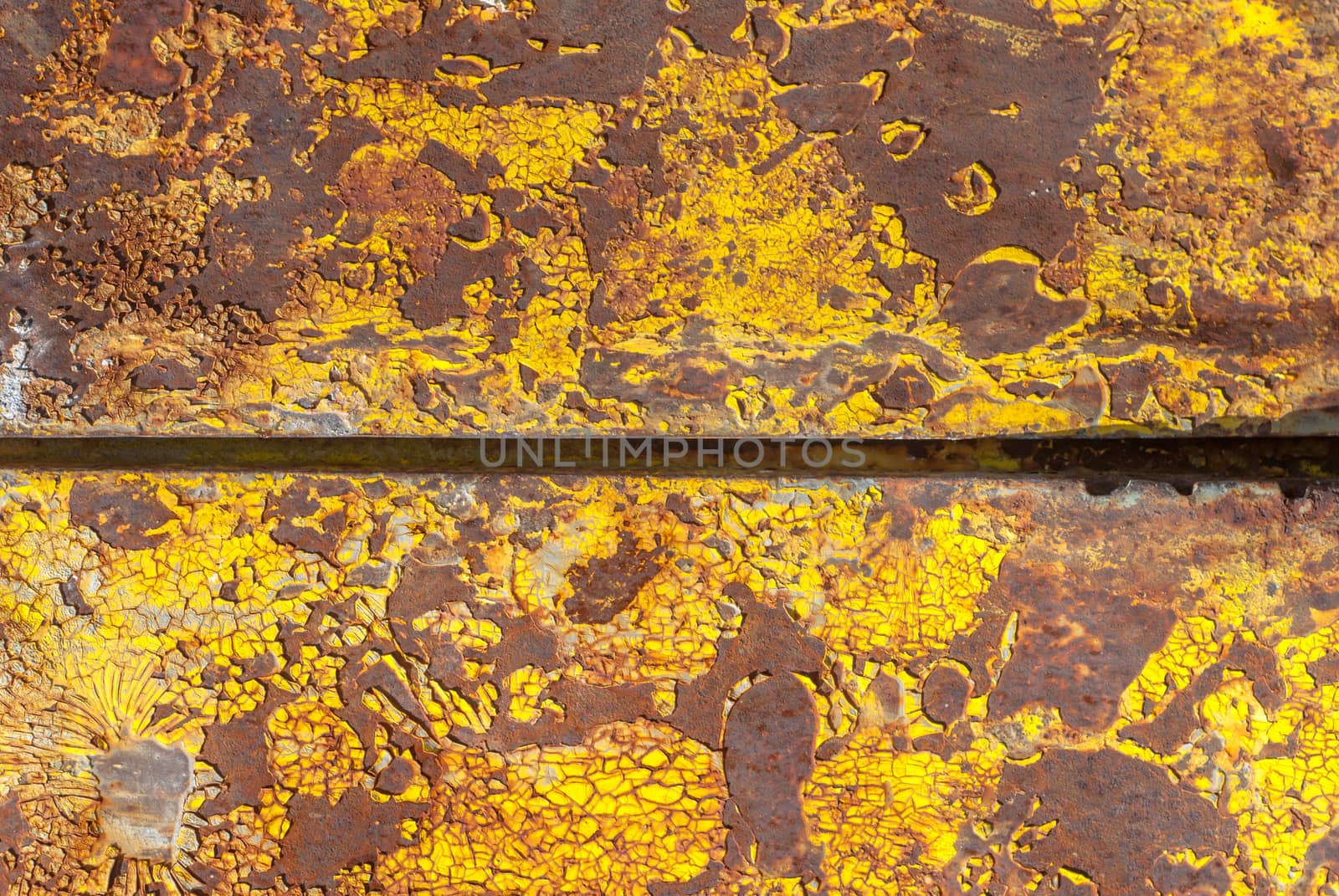 rusty iron surface covered with old chipped yellow color paint, which has long been influenced by different climatic conditions