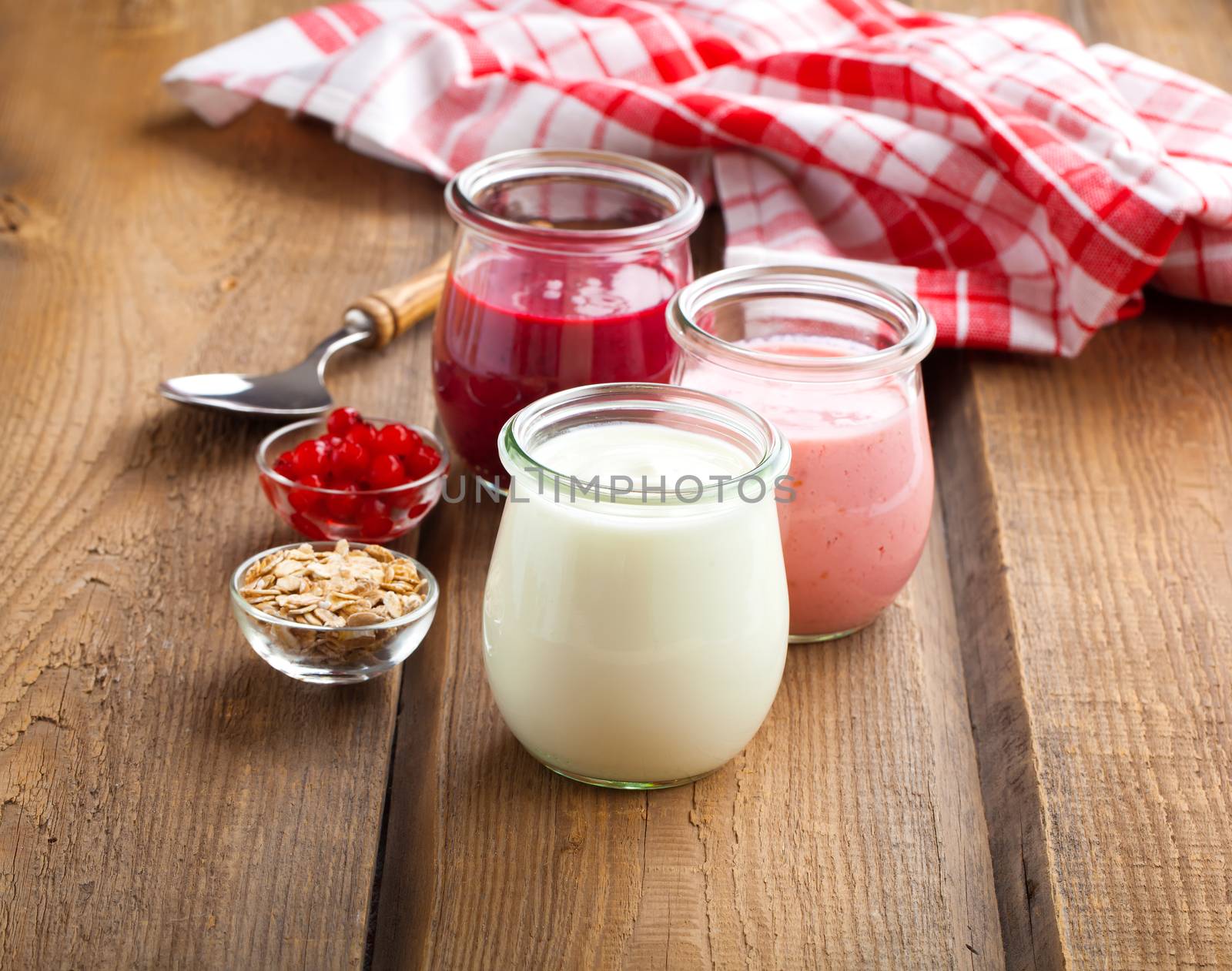 Healthy yougurt with berry in a glass jars on wooden background by motorolka