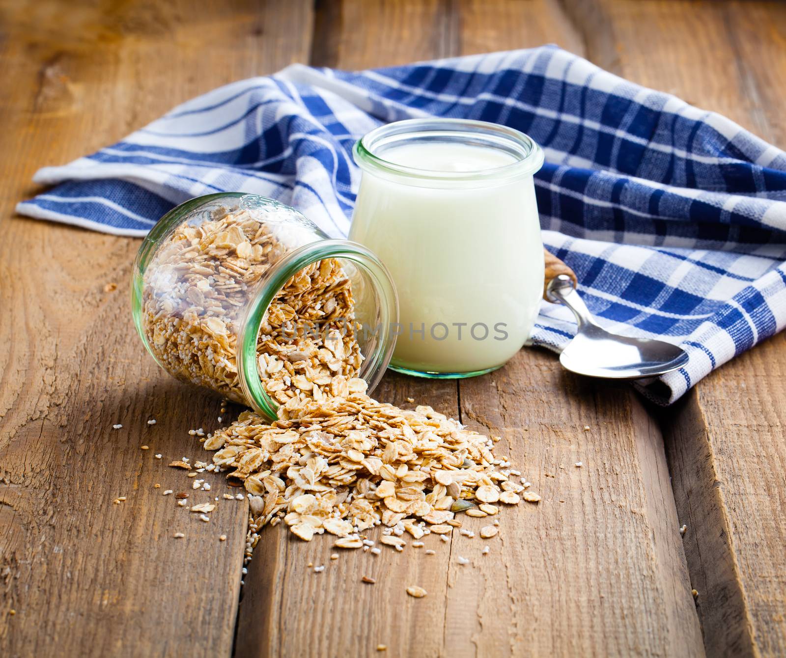 Healthy yougurt with oat flakes, in a glass jars on wooden background