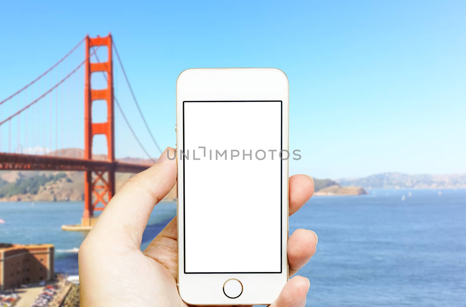 Mobile phone on hand with Golden Gate bridge in blue background.