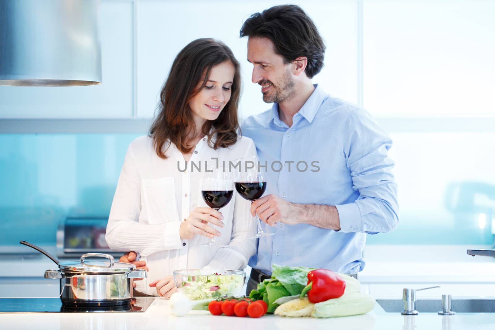 Portrait of a couple having a glass of red wine while cooking dinner