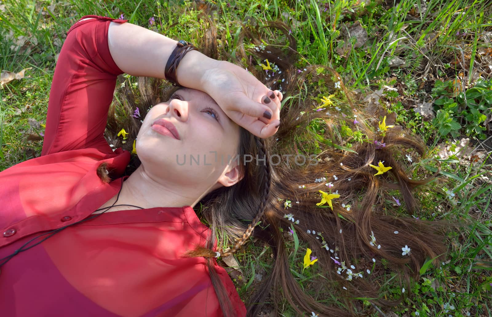 Portrait of young  girl  laying on grass with small flowers in her hair