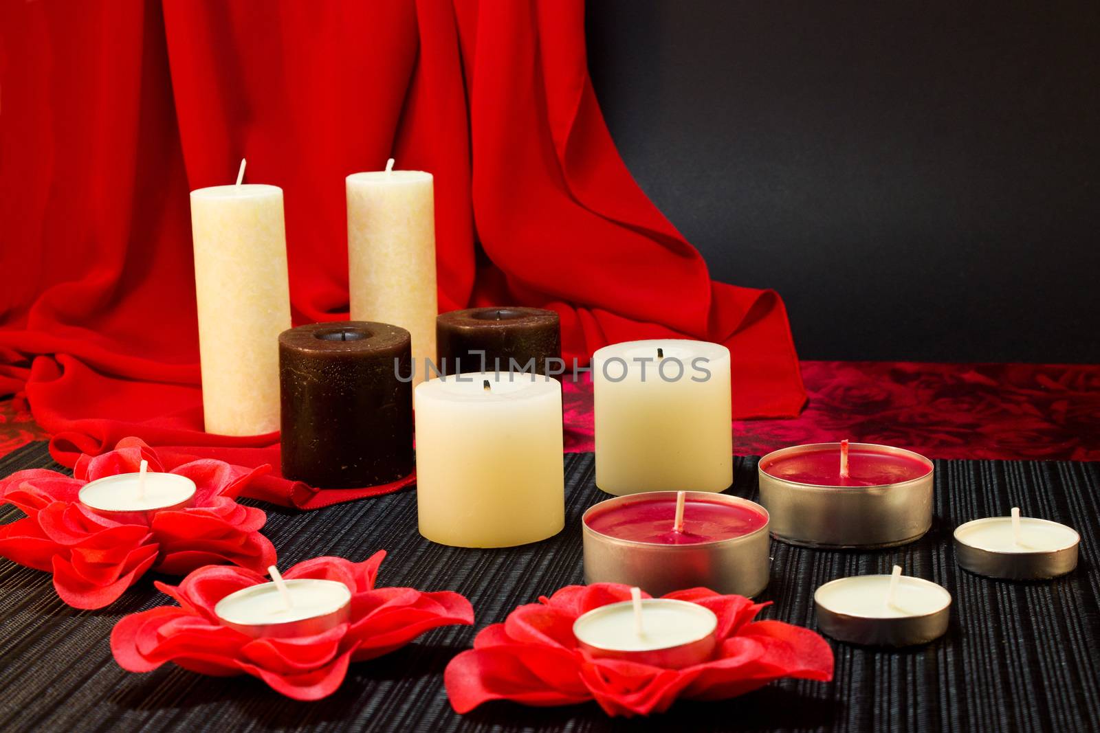 Still life of candles of different shapes on a black and red background