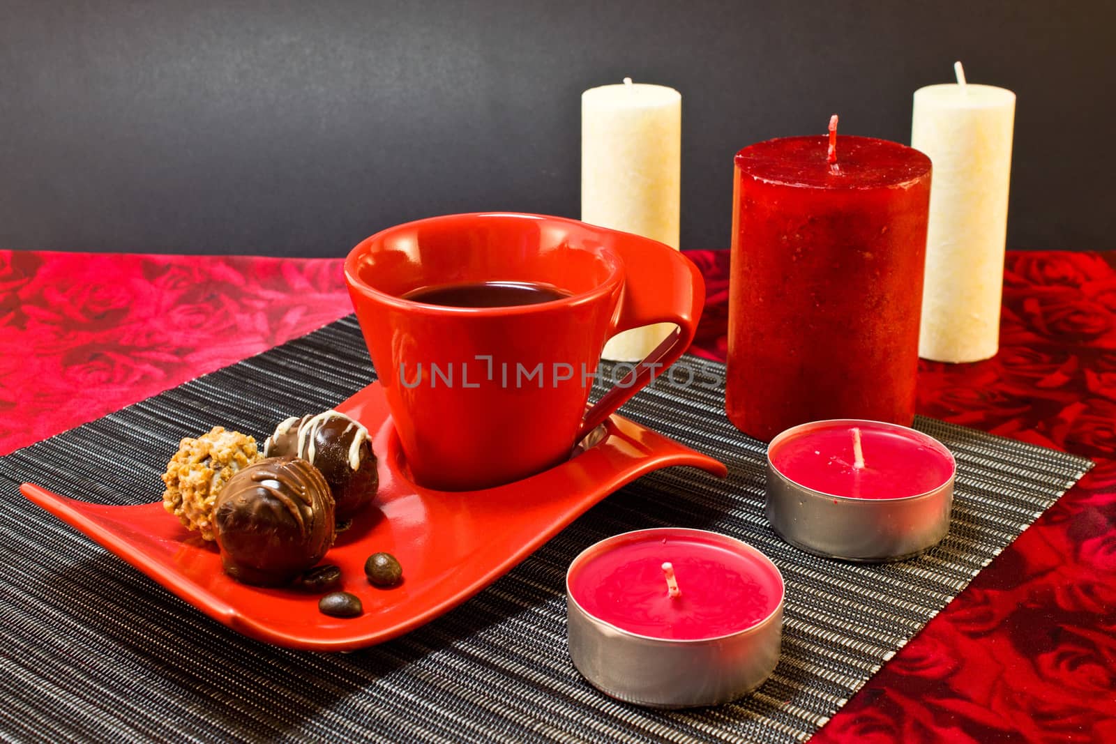 Still life of coffee in a red cup and saucer, and chocolates