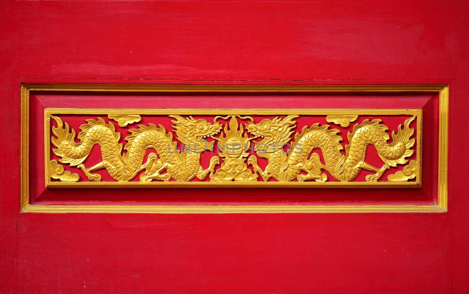 A coupple golden dragon on the red wall of Chinese temple in Thailand