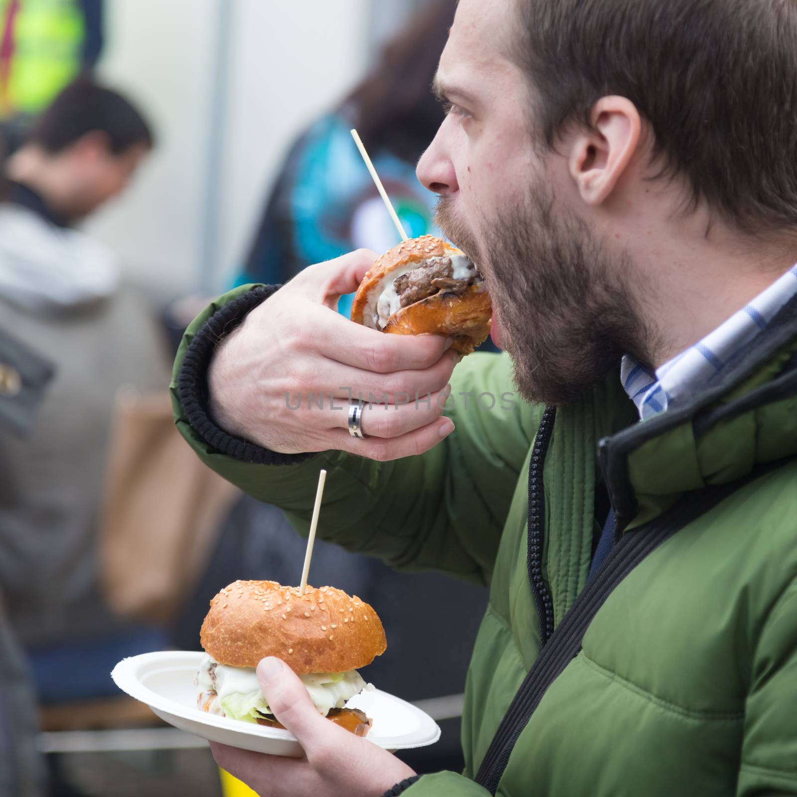 Man eating hamburgers on food festival in Ljubljana, Slovenia. by kasto