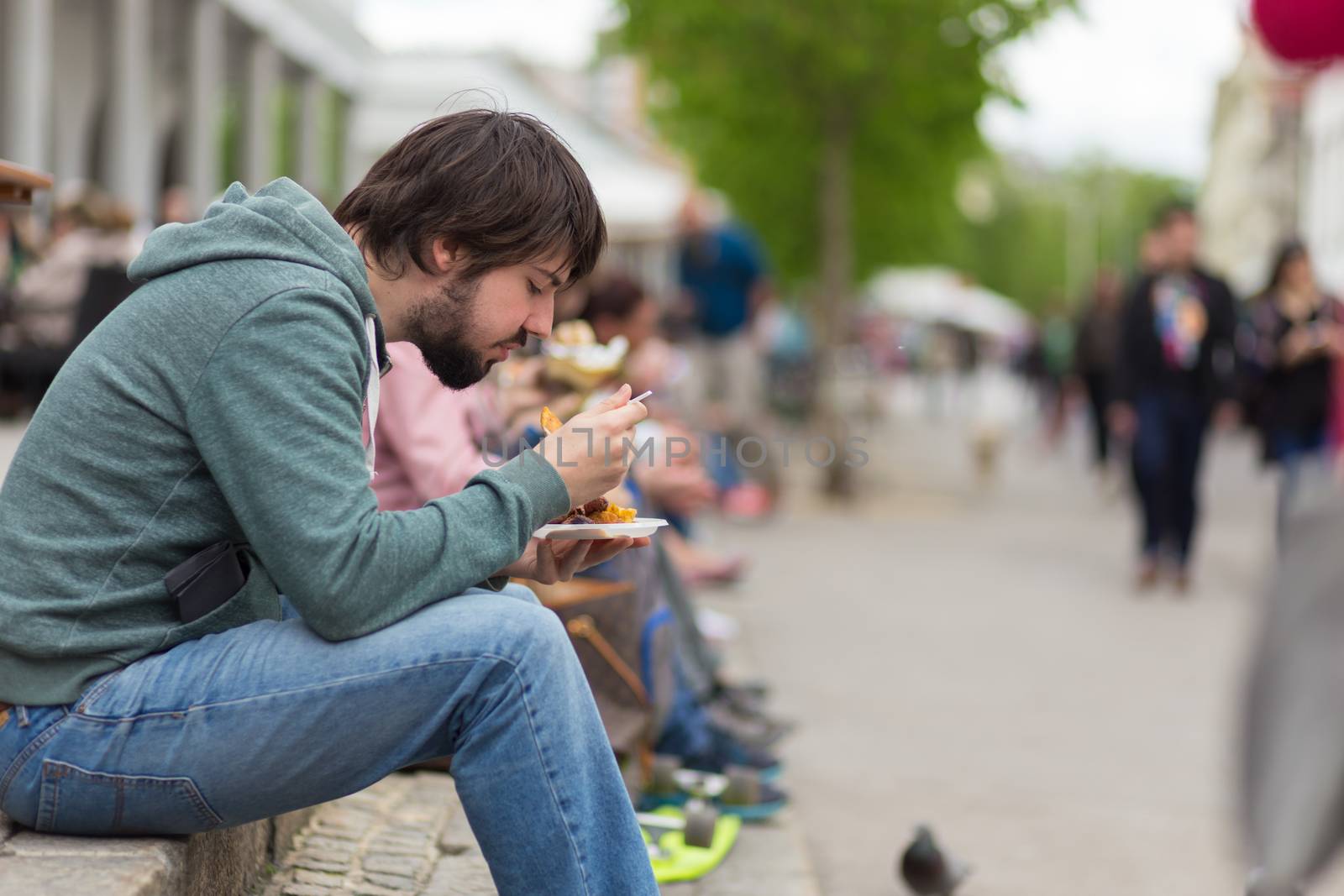 Ljubljana, Slovenia - April 15: Man enjoing outdoor street food festival of Odprta kuhna, Open kitchen event, on April 15th, 2016 in Ljubljana, Slovenia.