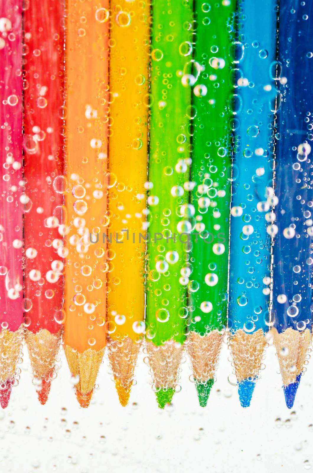 Close up colorful wooden pencils in sada water with bubbles