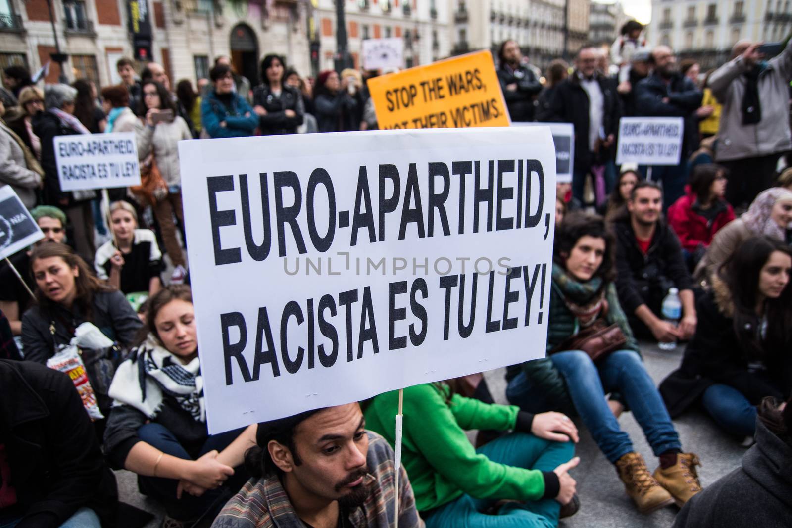 SPAIN, Madrid: A protester holds a sign which reads Euro-Apartheid, racista es tu ley! during a rally at Sol Square in Madrid, Spain on April 22, 2015 to protest against EU-Turkey agreement and to show support to refugees for a 24 hours vigil.