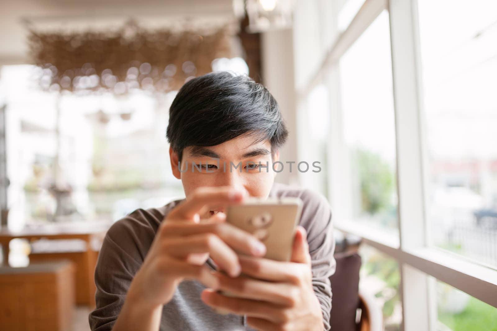 Smiling man using smartphone for online chat or shopping by nopparats