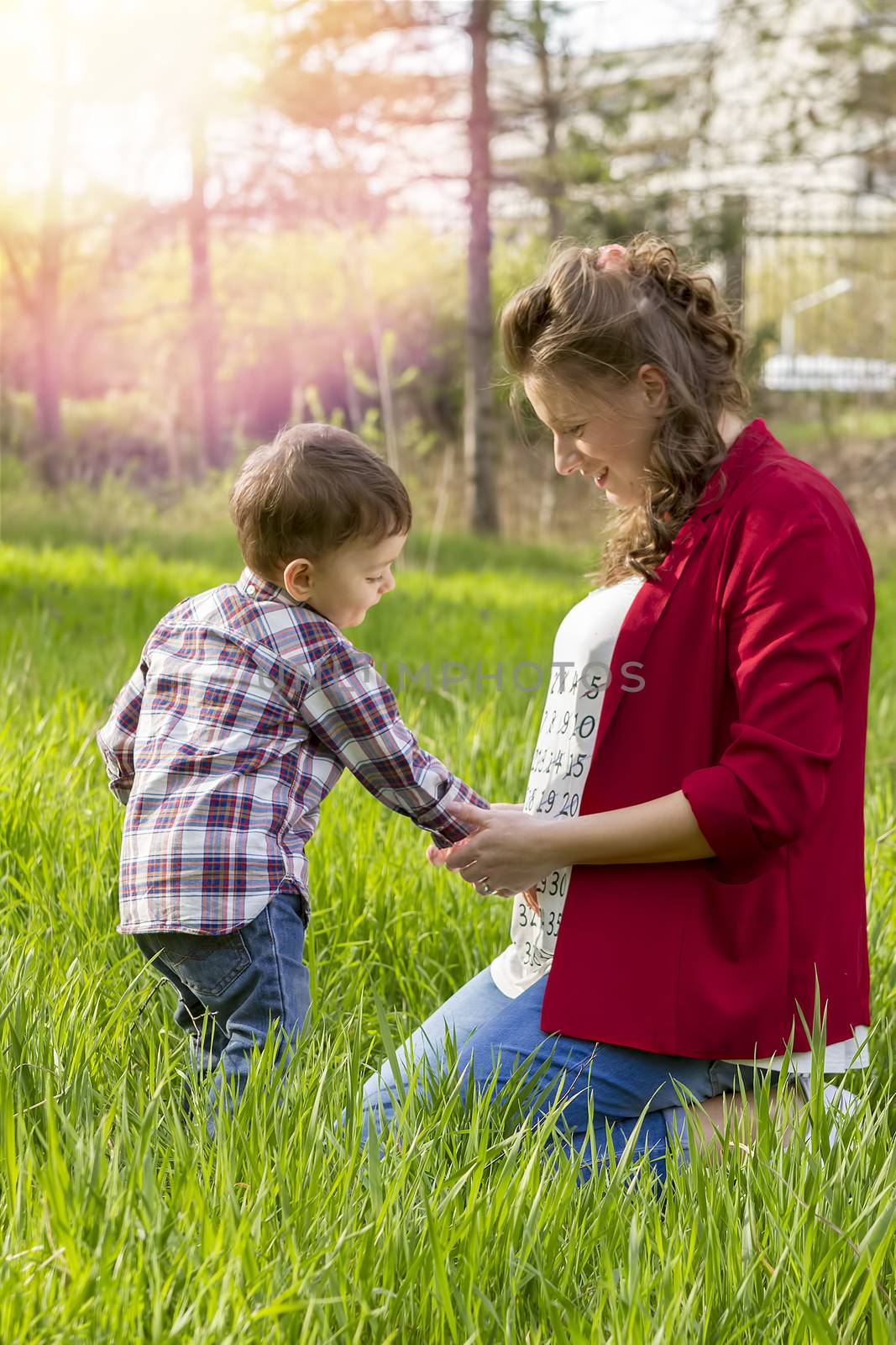 beautiful pregnant woman outdoor with her little boy in thr park