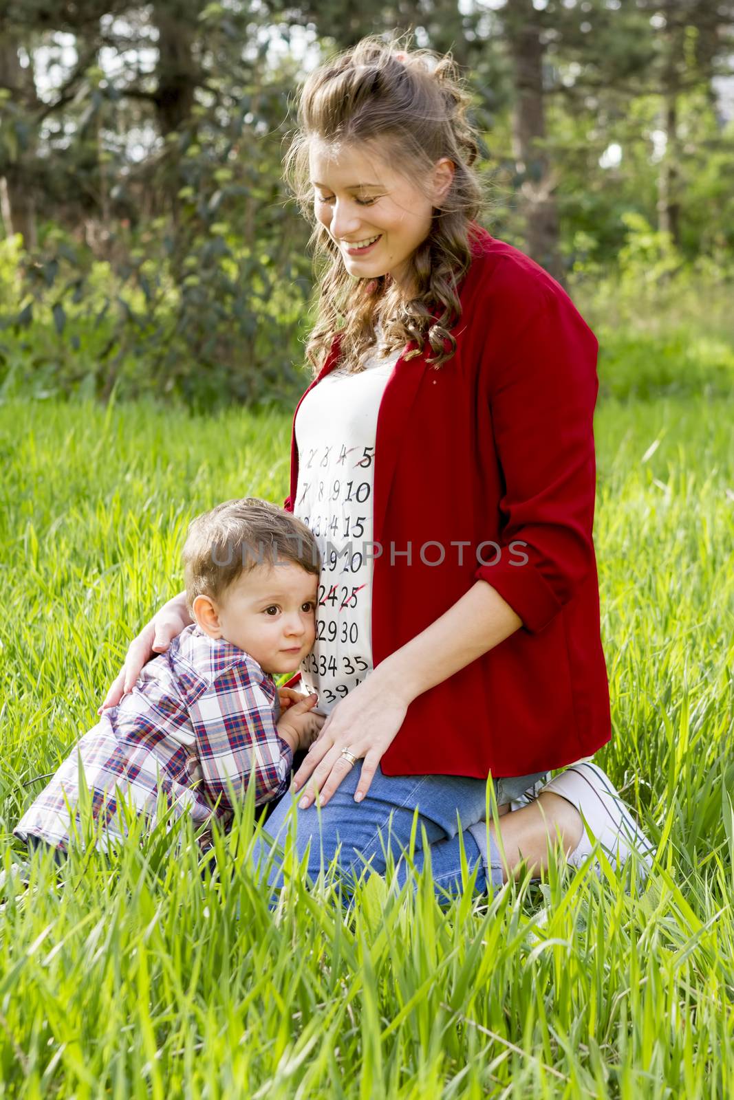 beautiful pregnant woman outdoor with her little boy in thr park