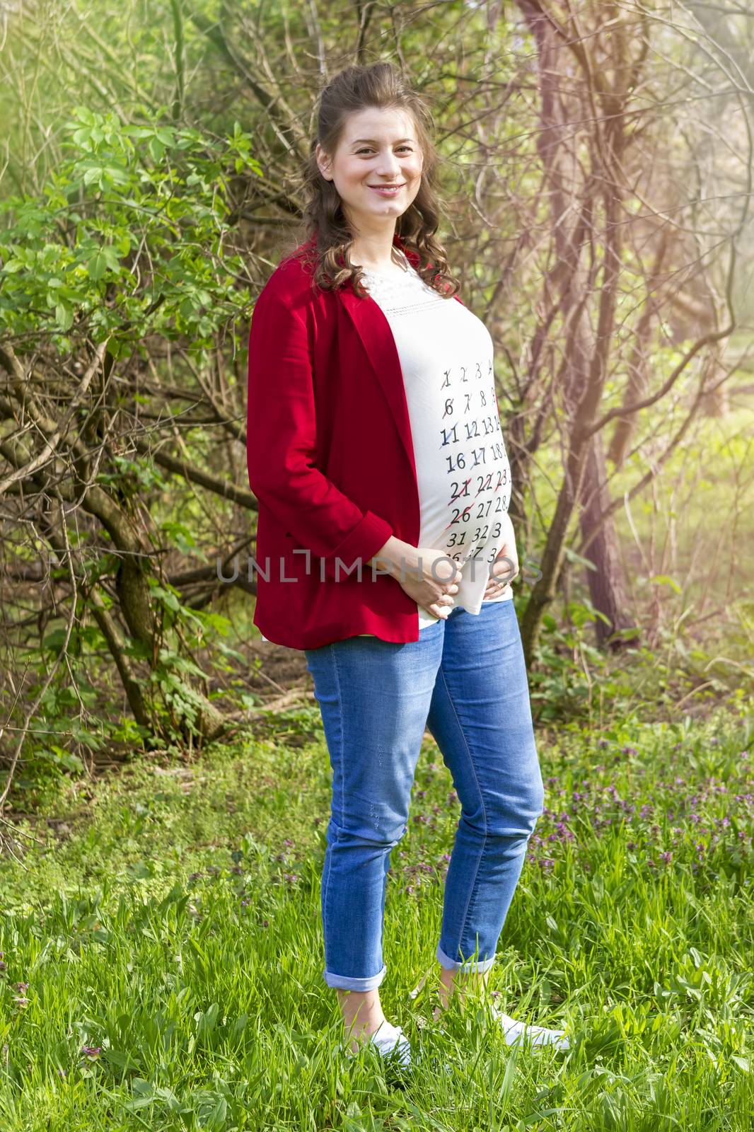 Pregnant woman in red jacket with calendar on her T-shirt  by manaemedia