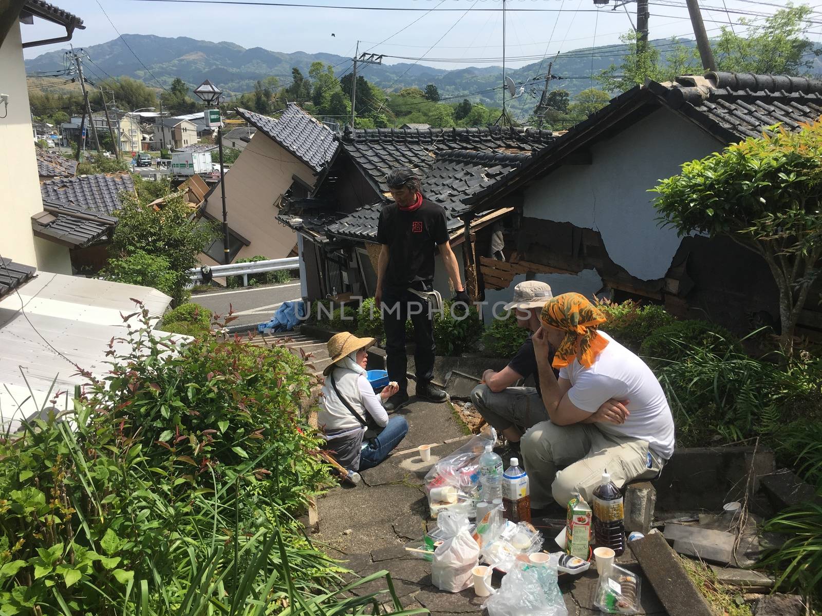 JAPAN, Mashiki: People have lunch in the rubble of collapsed neighborhood following an earthquake, on April 20, 2016 in Mashiki near Kumamoto, Japan. As of April 20, 48 people were confirmed dead after strong earthquakes rocked Kyushu Island of Japan. Nearly 11,000 people are reportedly evacuated after the tremors Thursday night at magnitude 6.5 and early Saturday morning at 7.3.