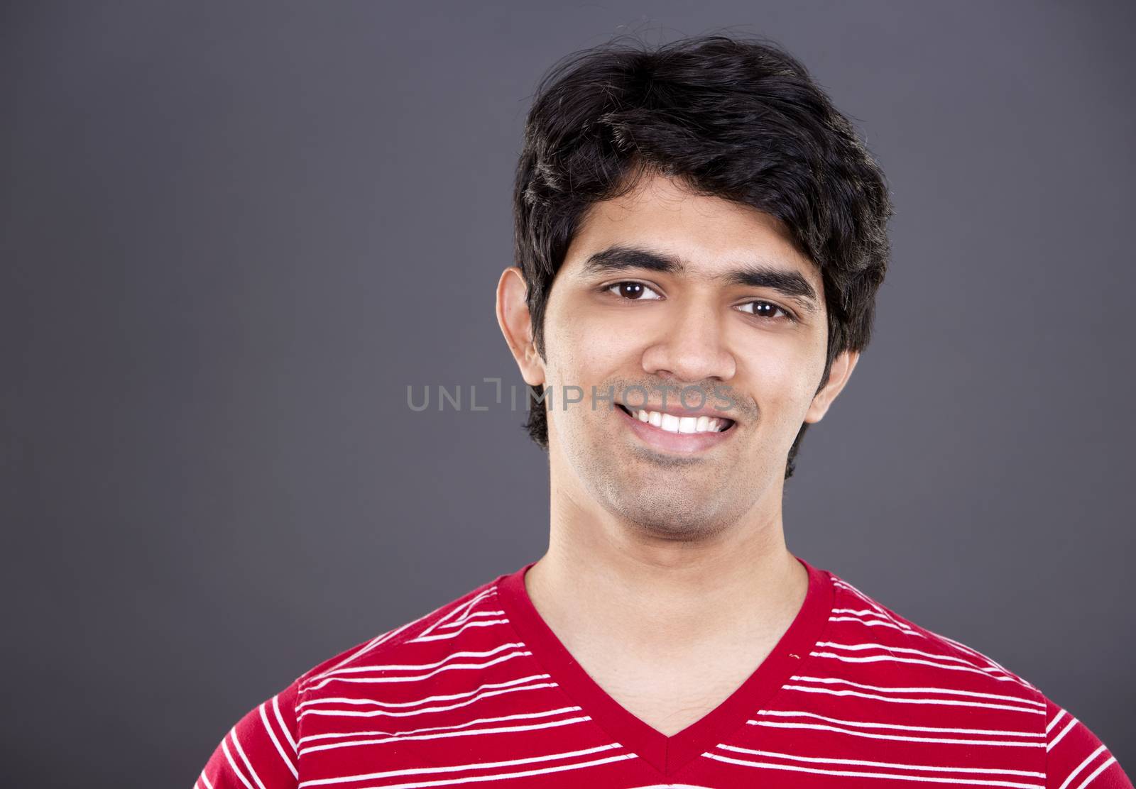 handsome east indian man wearing red shirt on light grey background