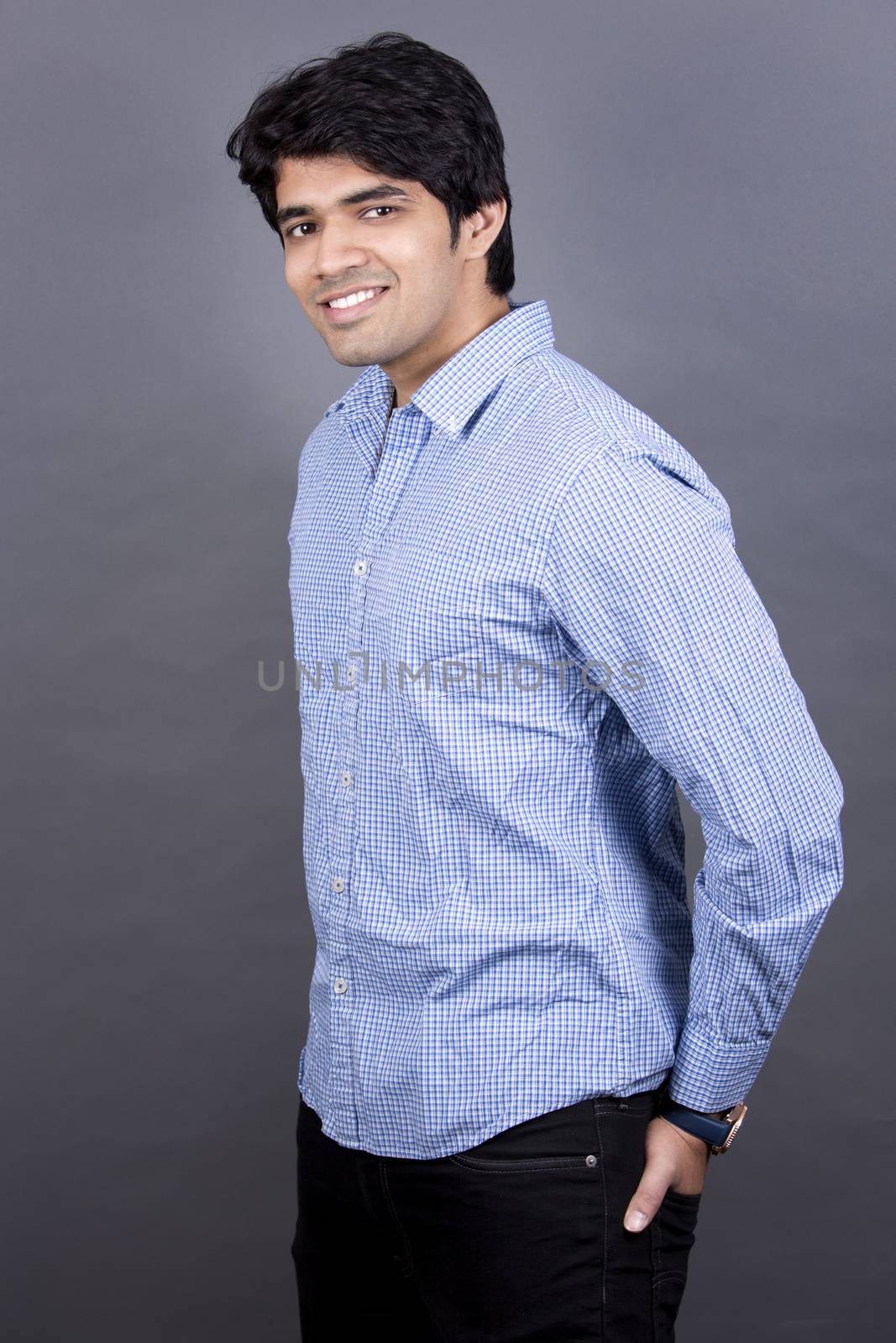 handsome east indian man wearing blue shirt on light grey background