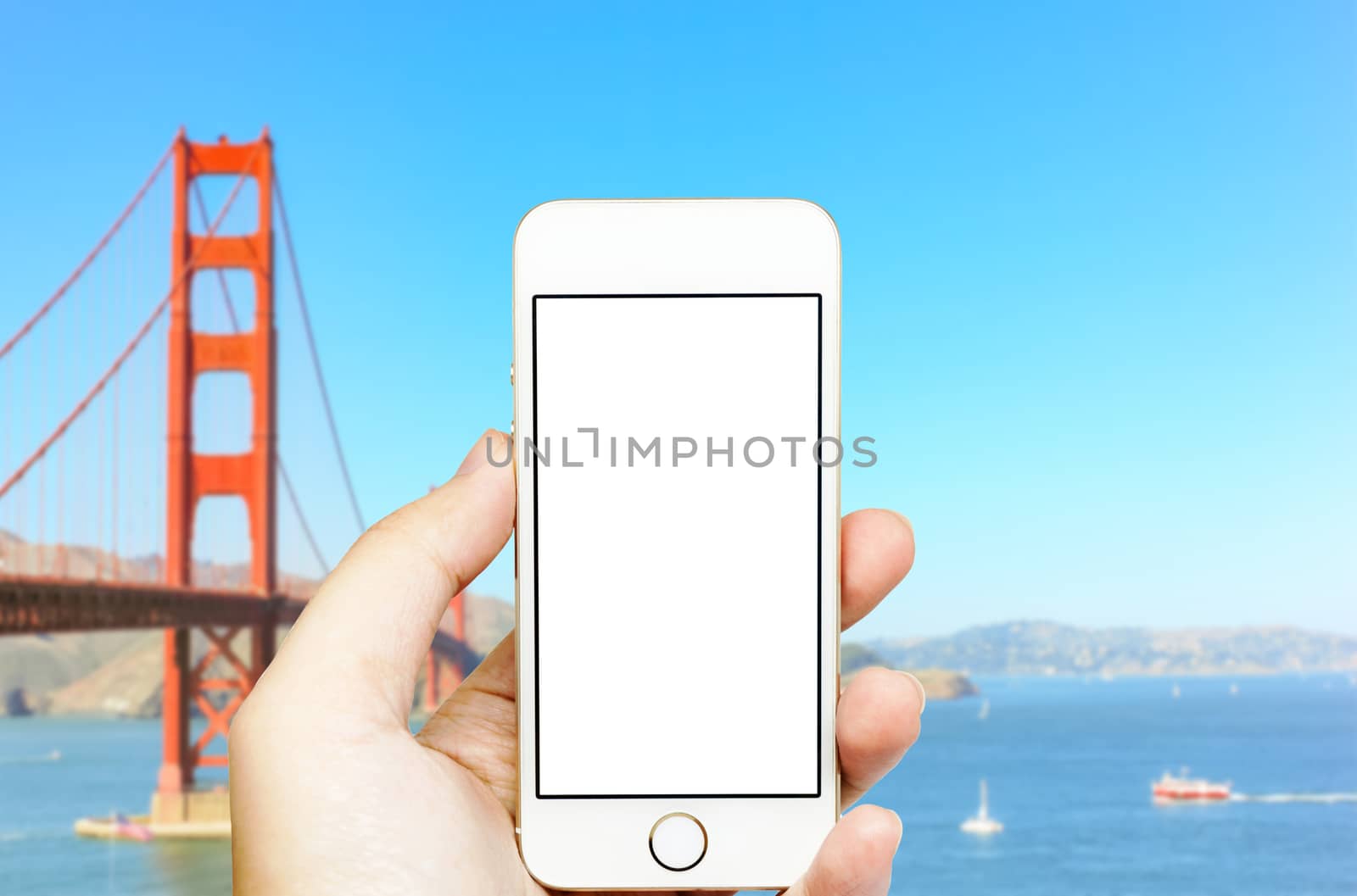 Mobile phone on hand with Golden Gate bridge in blue background.