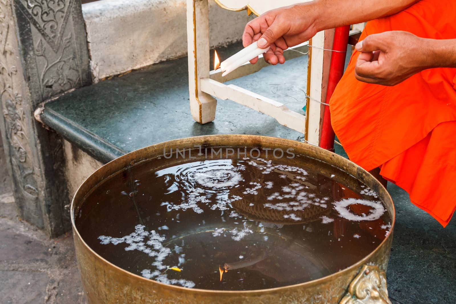 Thai monk making holy water with candle.