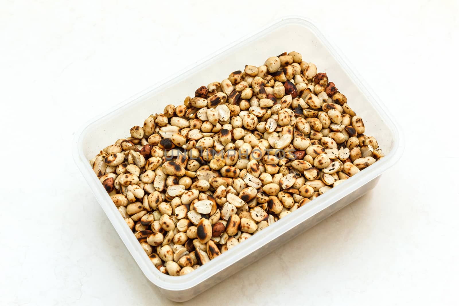 Pile of peeled roasted peanut in plastic box.