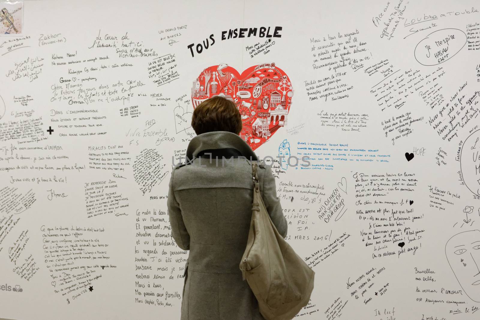 BELGIUM, Brussels : A woman reads messages on a commemorative wall at the Maelbeek - Maalbeek metro station on its re-opening day on April 25, 2016 in Brussels, after being closed since the 22 March attacks in the Belgian capital.Maelbeek - Maalbeek metro station was hit by one of the three Islamic State suicide bombers who struck Brussels airport and metro on March 22, killing 32 people and injuring hundreds.