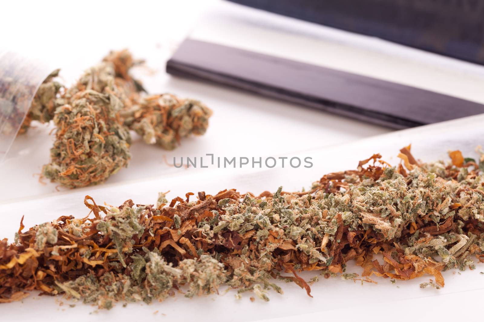 Close up Dried Cannabis Leaves on a Resealable Cellophane Wrapper and a Rolling Paper with Filter on Top of the Table