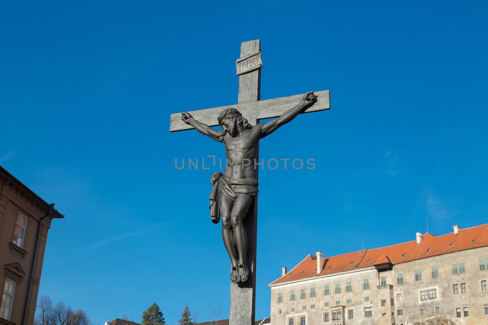 Close up detailed view of a crucifixe Jesus sculpture, on bright blue sky background.