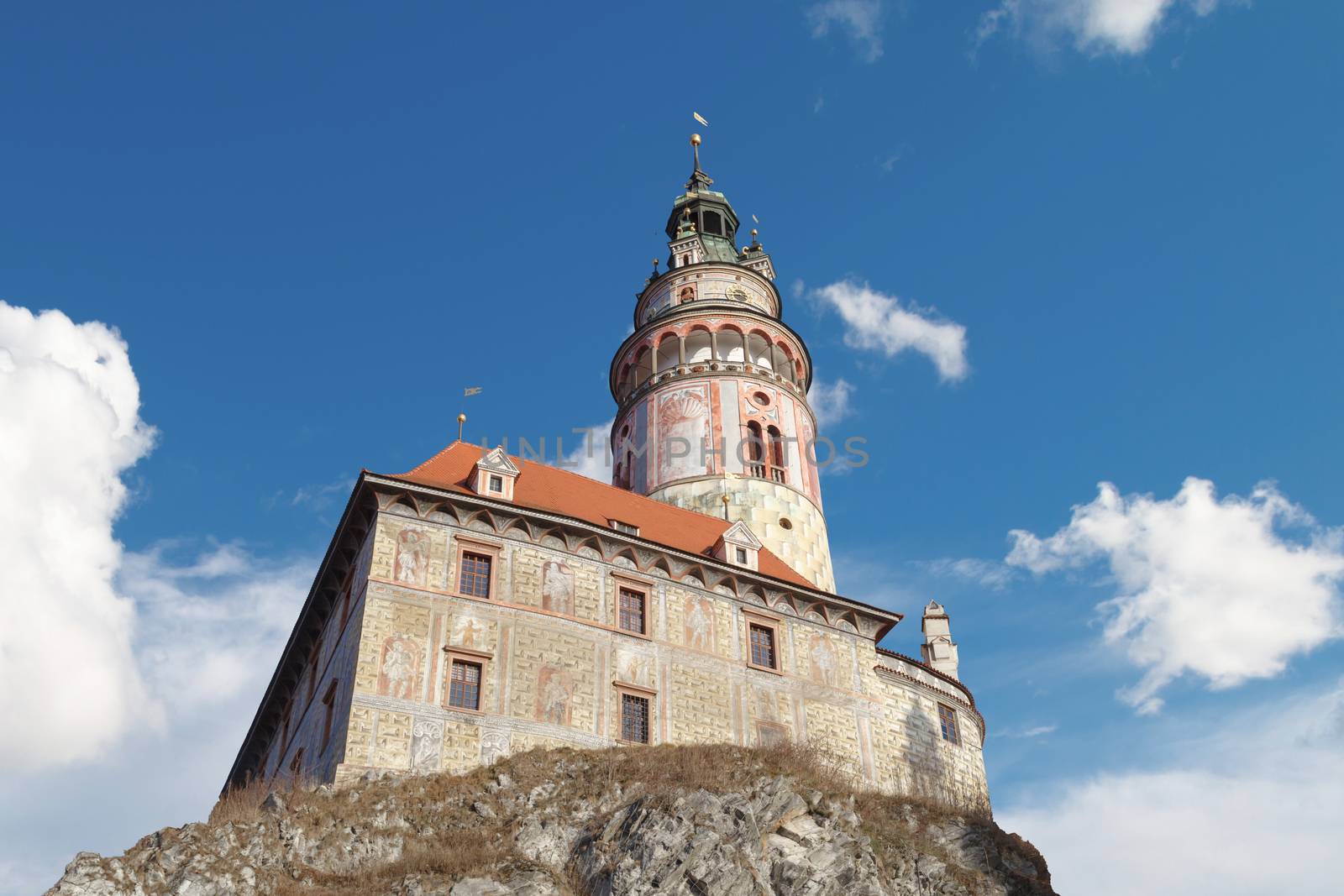 General view of Little Castle Tower in Cesky Krumlov, colorful historical tower on cloudy blue sky background.