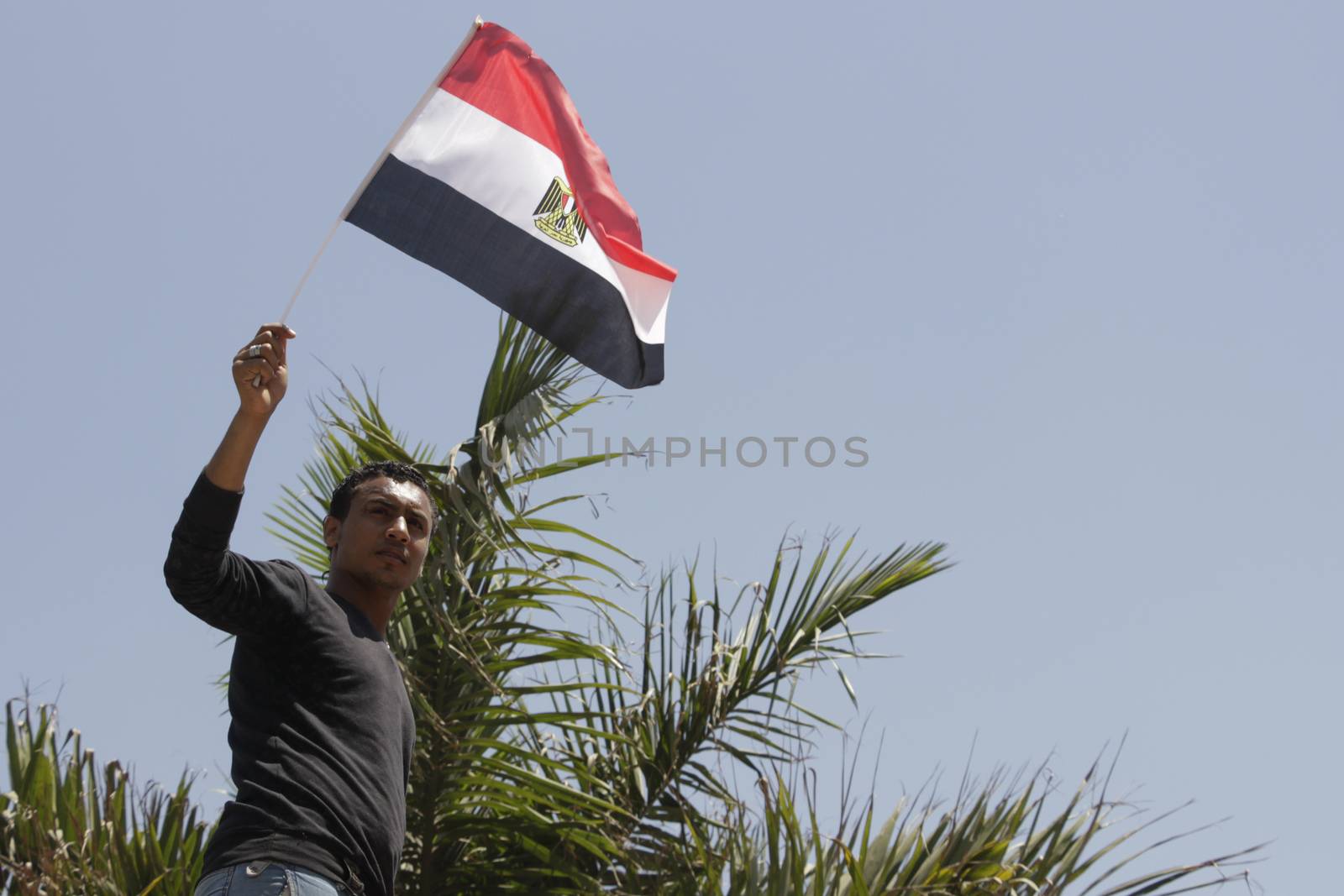 EGYPT, Giza: A man waves national flag as dozens hold portraits of Egyptian president Abdel-Fattah el-Sissi reading Long live Egypt and gather in Mostafa Mahmoud Square in Giza, near Cairo on April 25, 2016 to commemorate the thirty-fourth anniversary of Sinai liberation. This same day, thousands of security personnel were deployed around Cairo ahead of mass planned protests over the return of two Red Sea islands to Saudi Arabia, a decision that has provoked some of the most open criticism of President Abdel-Fattah el-Sissi's leadership.