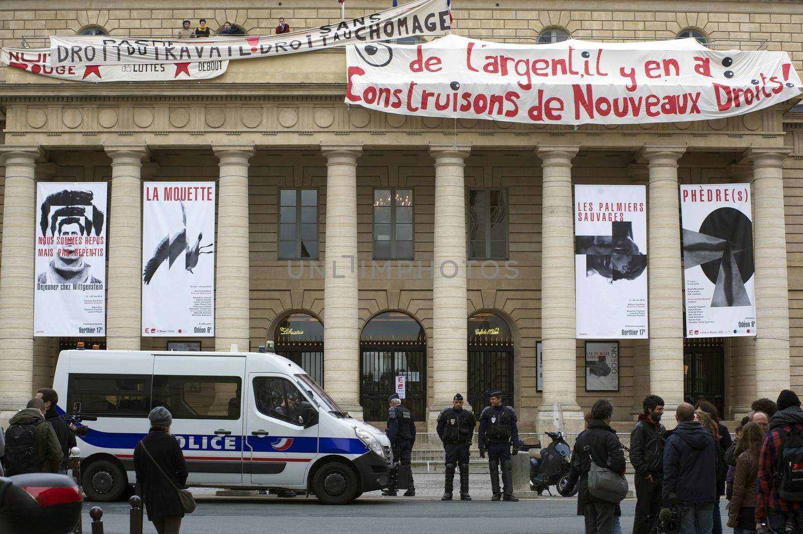 FRANCE, Paris : Policemen stand guard outside the Odeon theatre as French artists and entertainment workers known in France as intermittents du spectacle occupy the building and display a banner reading There is money, let's build new rights in Paris on April 25, 2016.Around 50 people occupied the building to protest against the French government's proposed labour reforms and to demand the reshaping of the unemployment insurance before the start of the unemployment insurance negotiations, as part of a protest in conjunction with the Nuit Debout (Night Rising) movement against the French government's proposed labour reforms. 