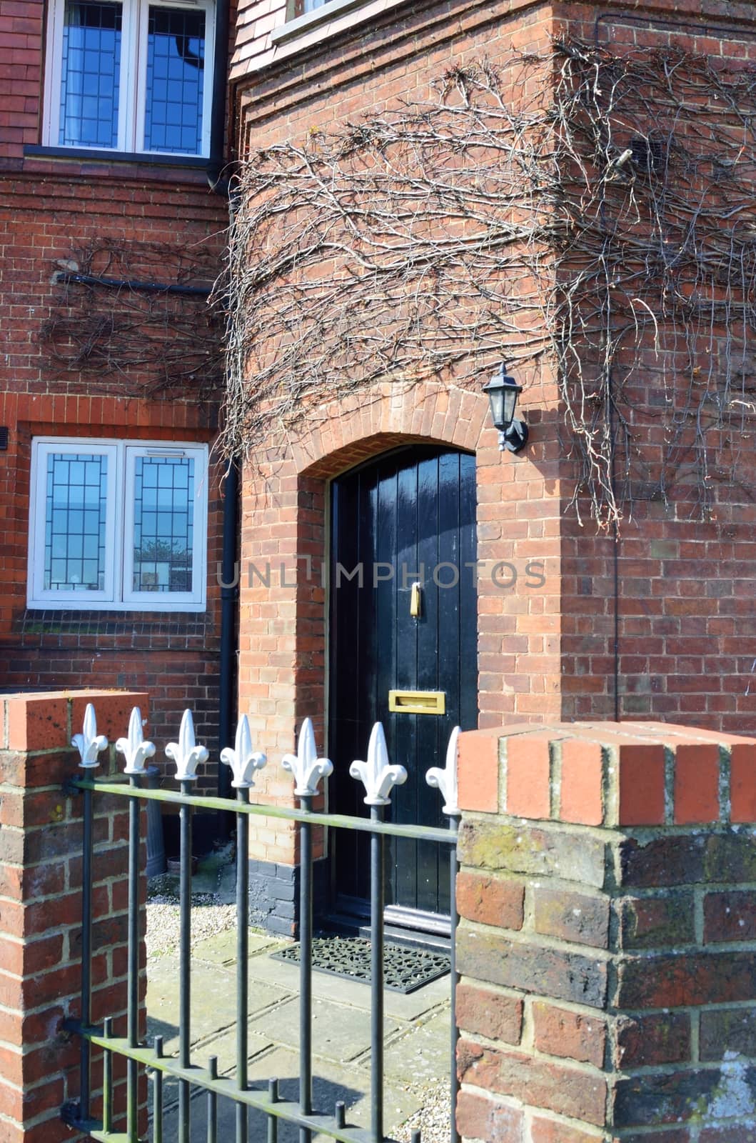 Black doorway with brick and metal fence