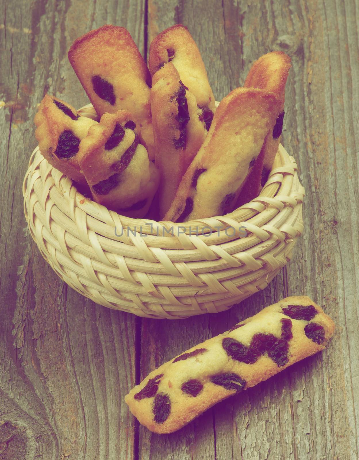Tasty Biscuit Raisin Cookies in Wicker Bowl closeup on Rustic Wooden background. Retro Styled