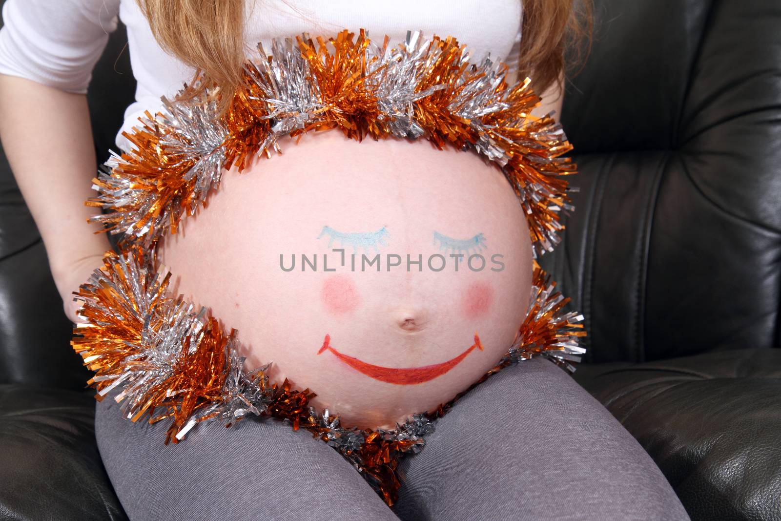 Pregnant woman with painted eyes on his stomach and mouth