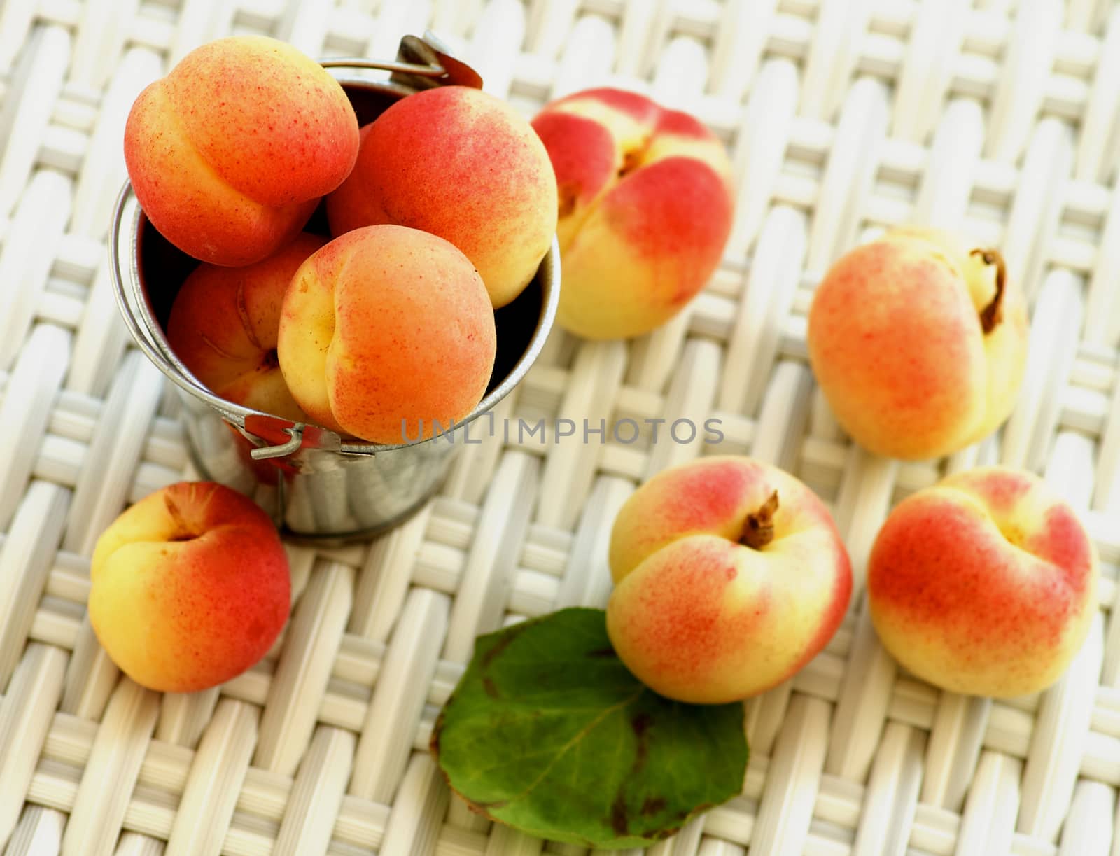 Arrangement of Ripe Fresh Apricots in Tin Bucket closeup on Wicker background. Focus on Top of Heap