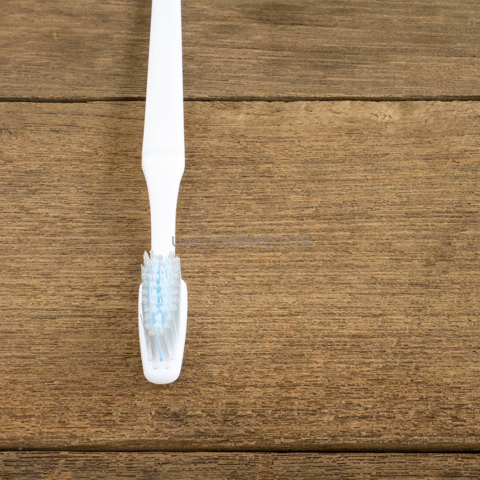 The clean white toothbrush on old wooden planks for brushing the teeth.