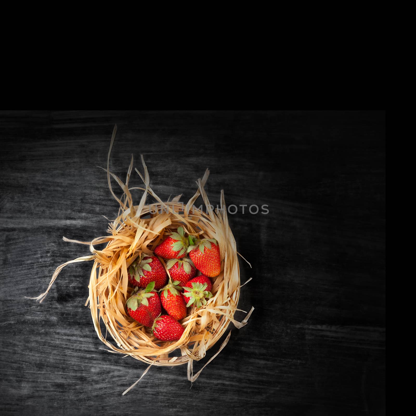 Juicy strawberries in basket on dark background