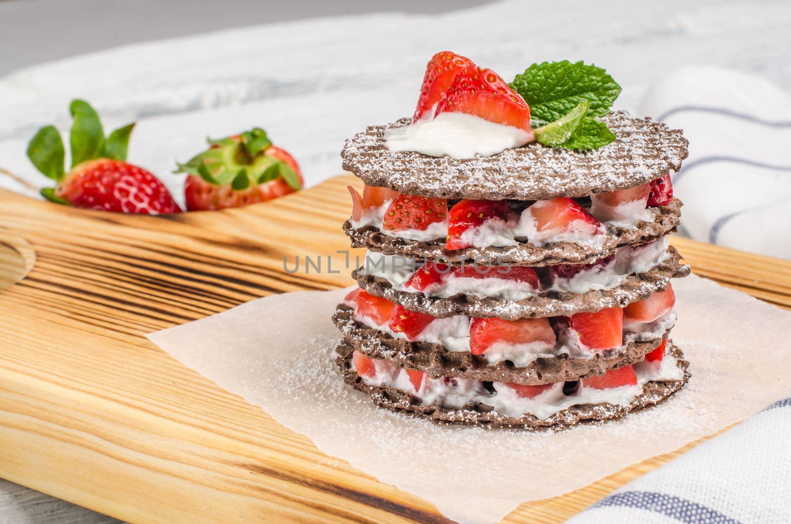 Chocolate belgian waffles with strawberries, whipped cream and mint leaf on wooden table