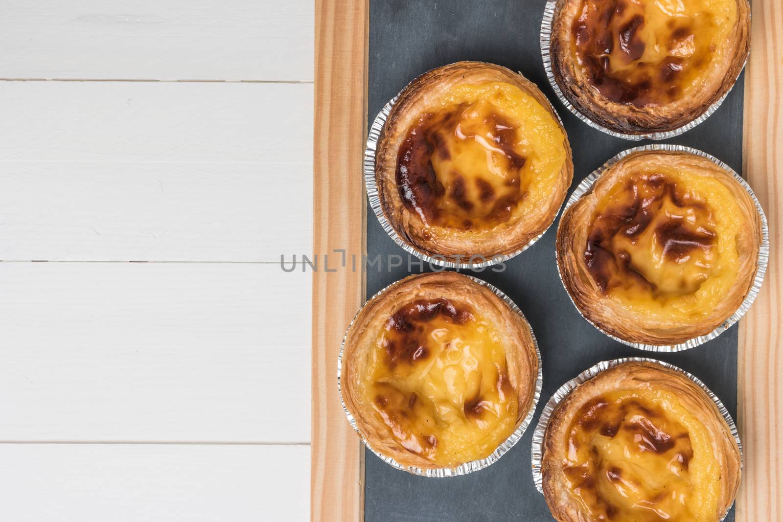 Pasteis de nata, typical Portuguese egg tart pastries on a set table. Top view with copy space