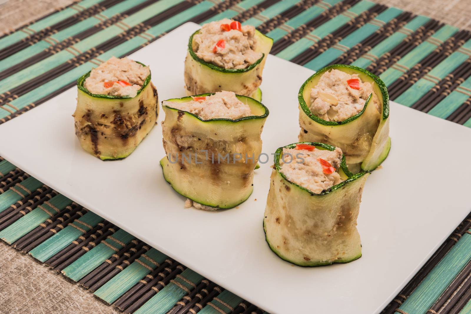 Grilled zucchini rolls with curd cheese and tuna on plate. Top view with copy space
