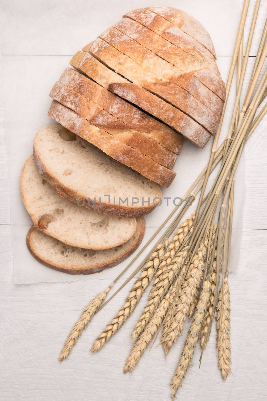Fresh homemade bread and wheat spike on wooden background. Top view with copy space.