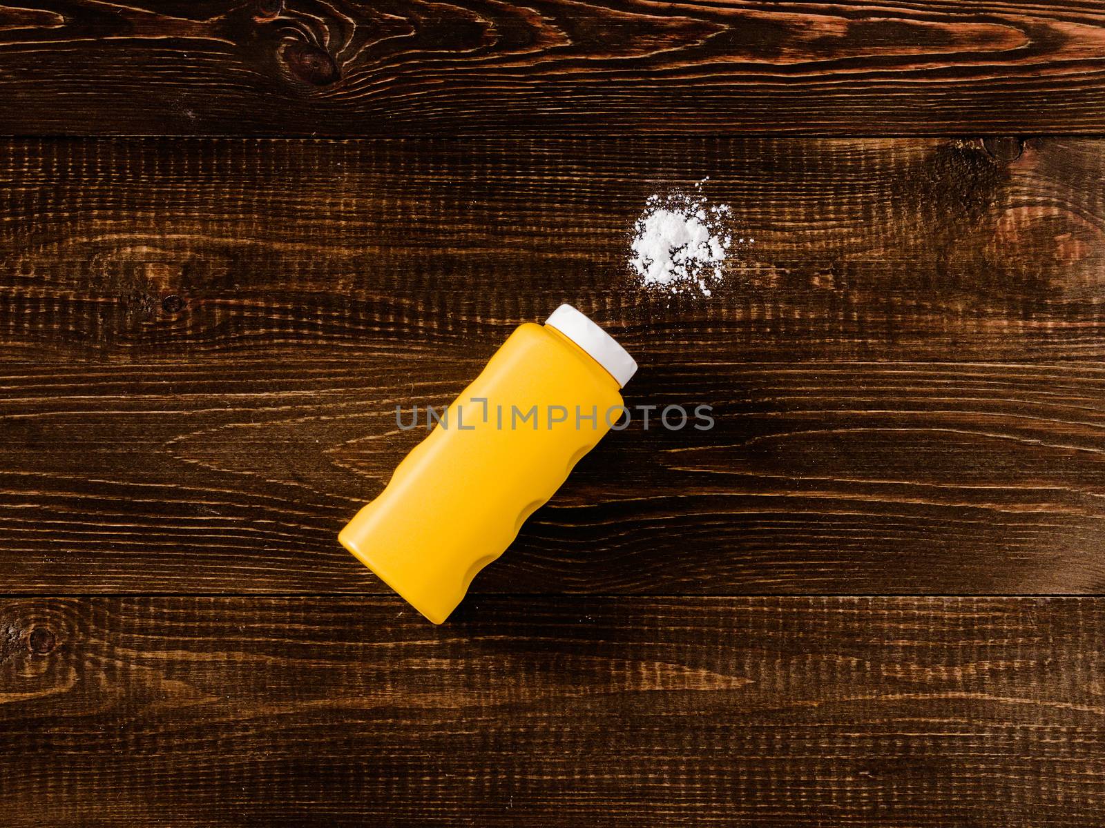 Spilled baby talcum powder on dark wooden background. Flat lay