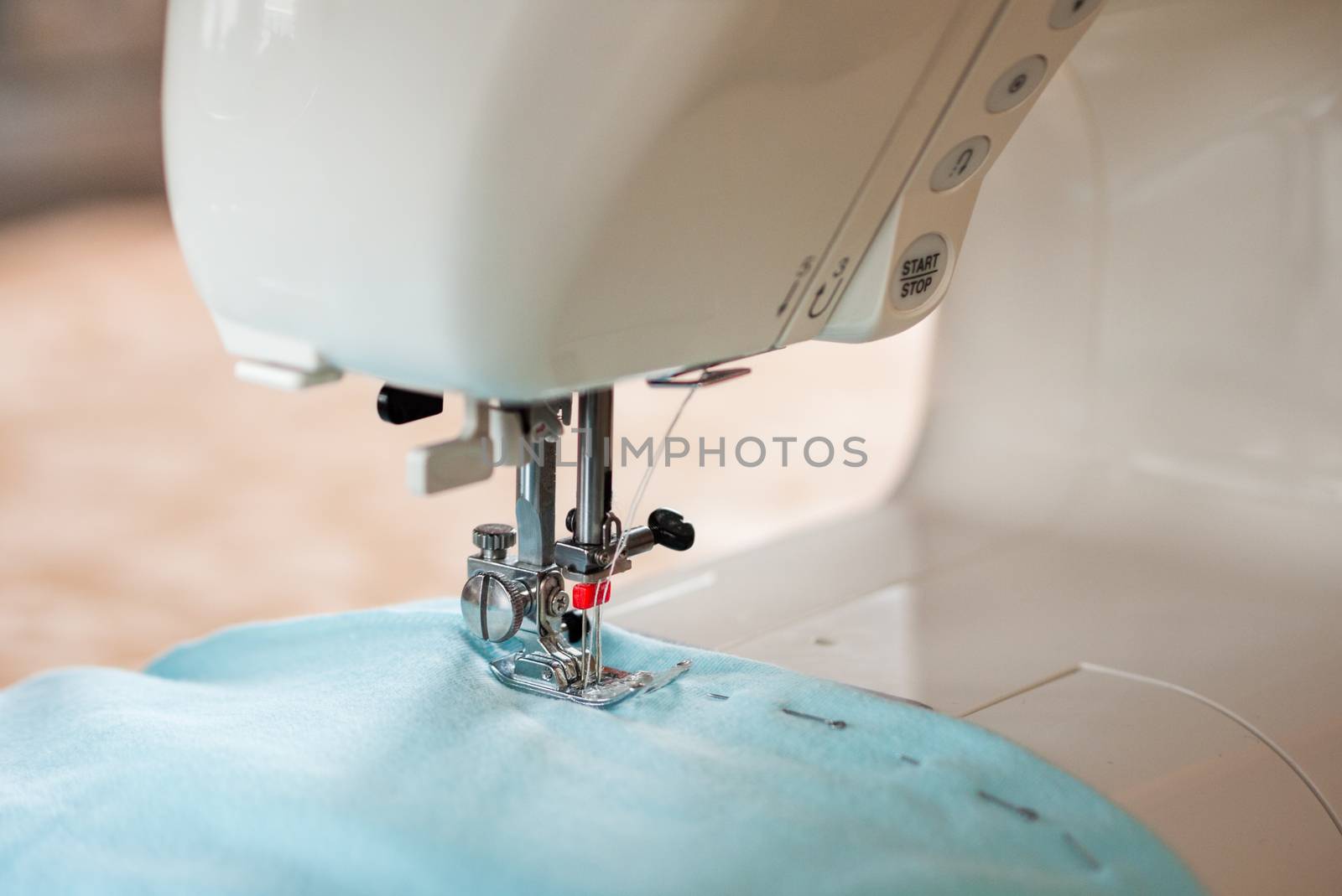 Sewing process. Sewing machine with twin needle and blue fabric