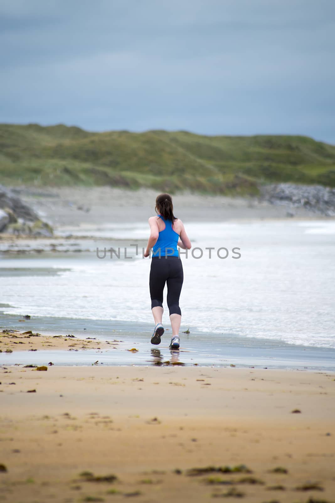 young woman jogging on the beach in ballybunion county kerry ireland