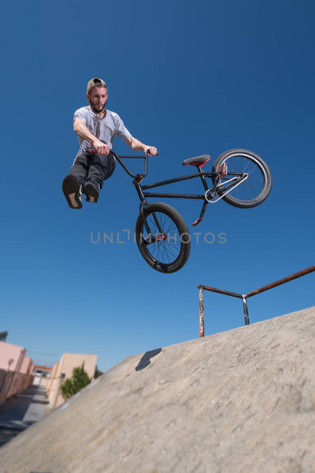 Bmx rider performing a tail whip at a quarter pipe ramp on a skatepark.