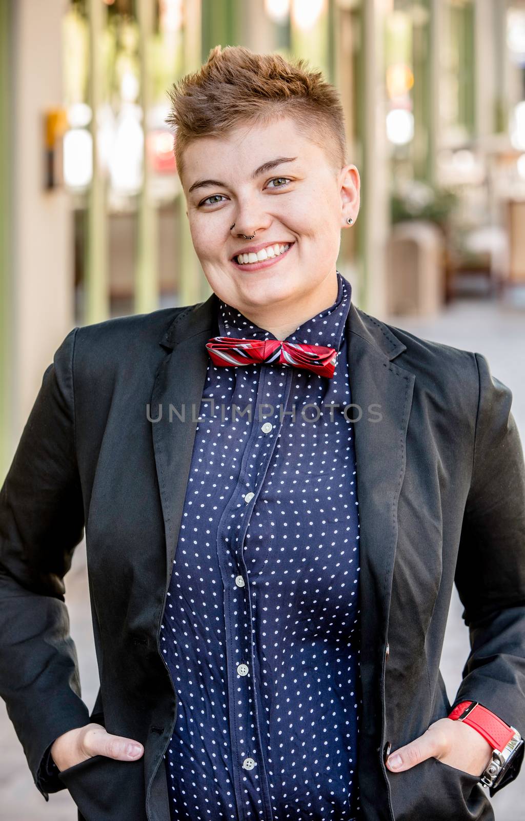 Smiling dapper young gender fluid woman on city sidewalk