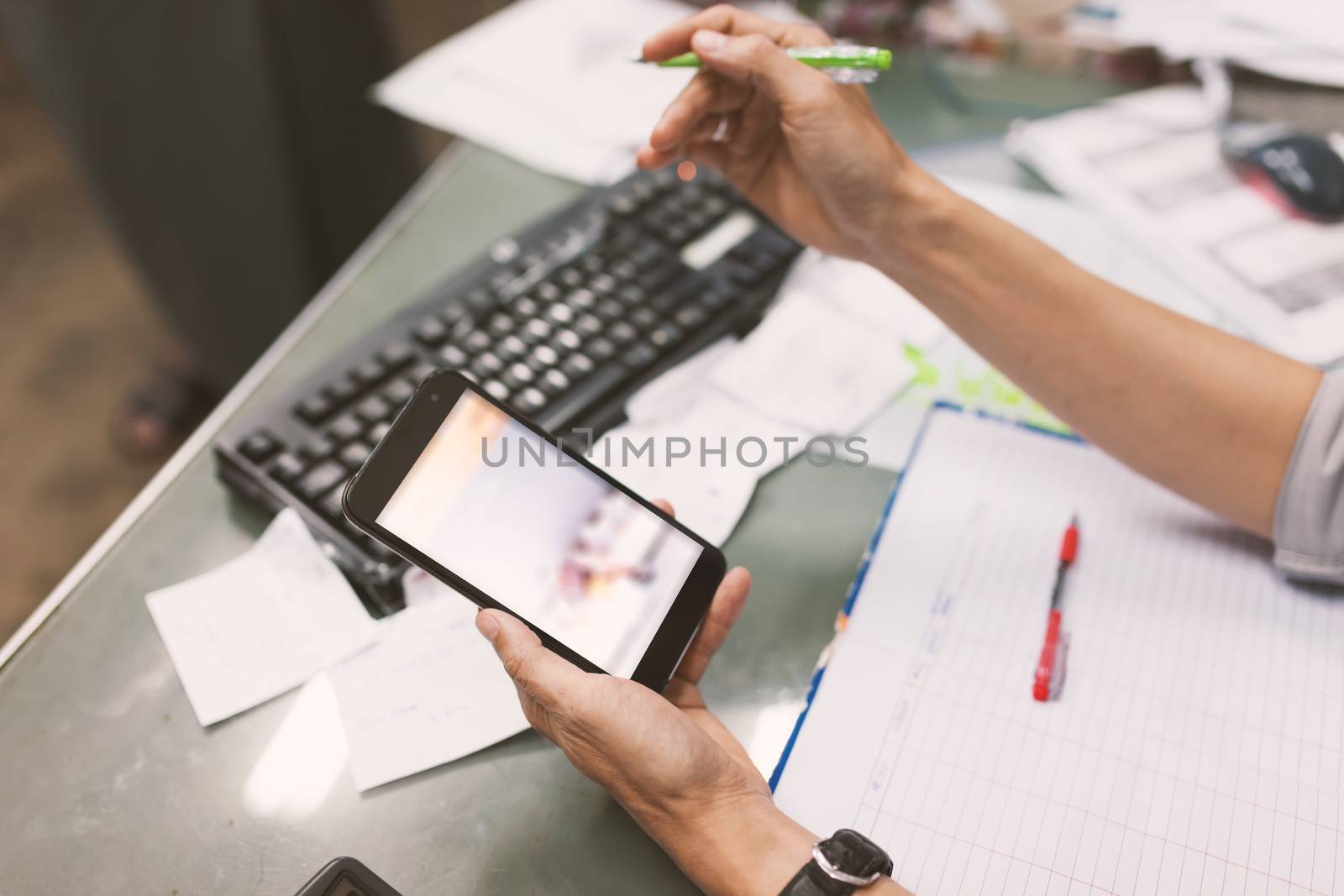 Close up of hand of business man working document and using mobile smart phone in office .