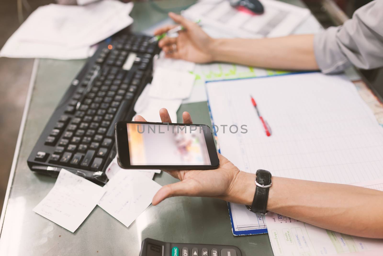 Close up of hand of business man working document and using mobile smart phone in office .