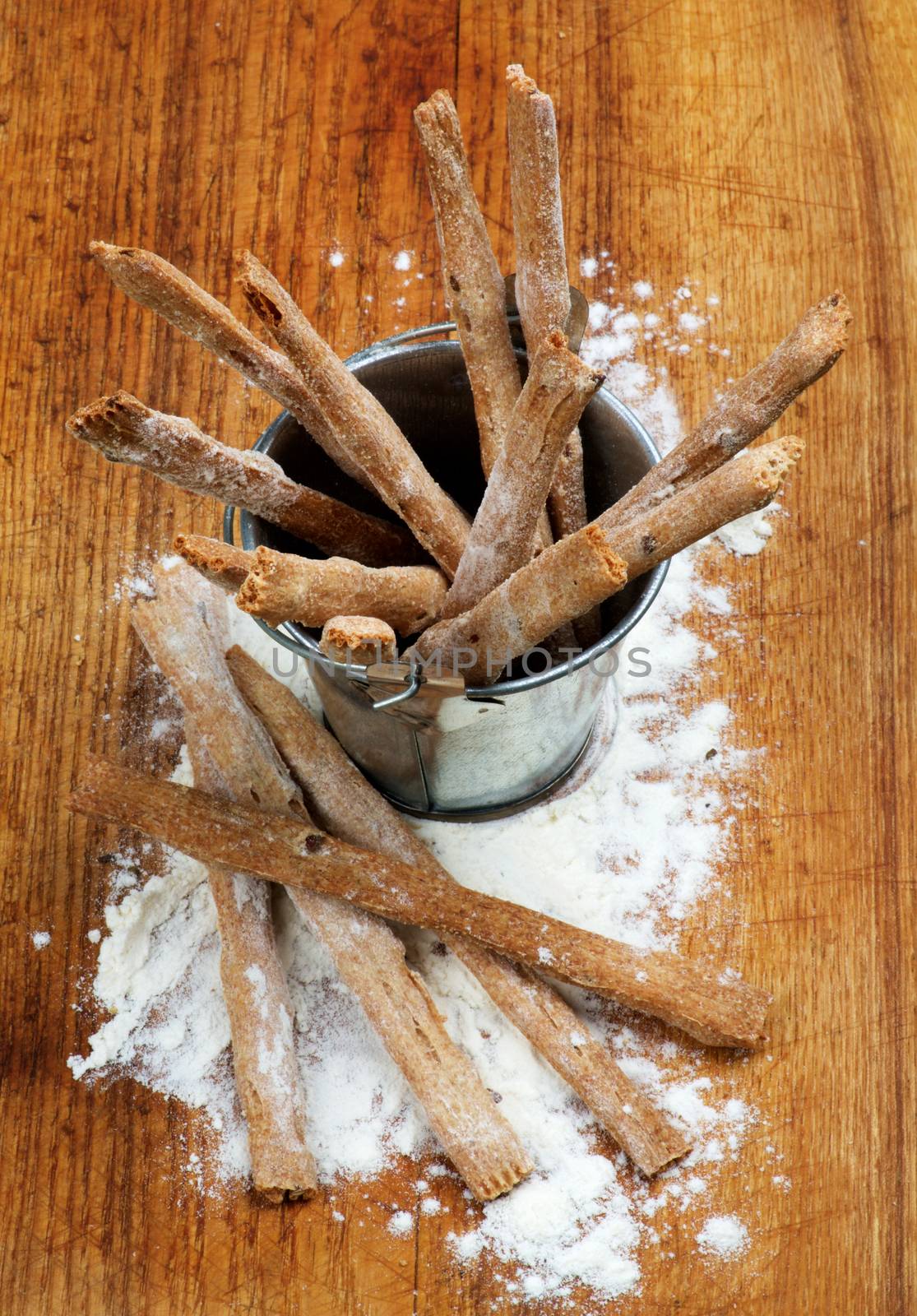 Freshly Baked Whole Wheat Bread Sticks in Tin Bucket with Dough closeup on Wooden Cutting Board